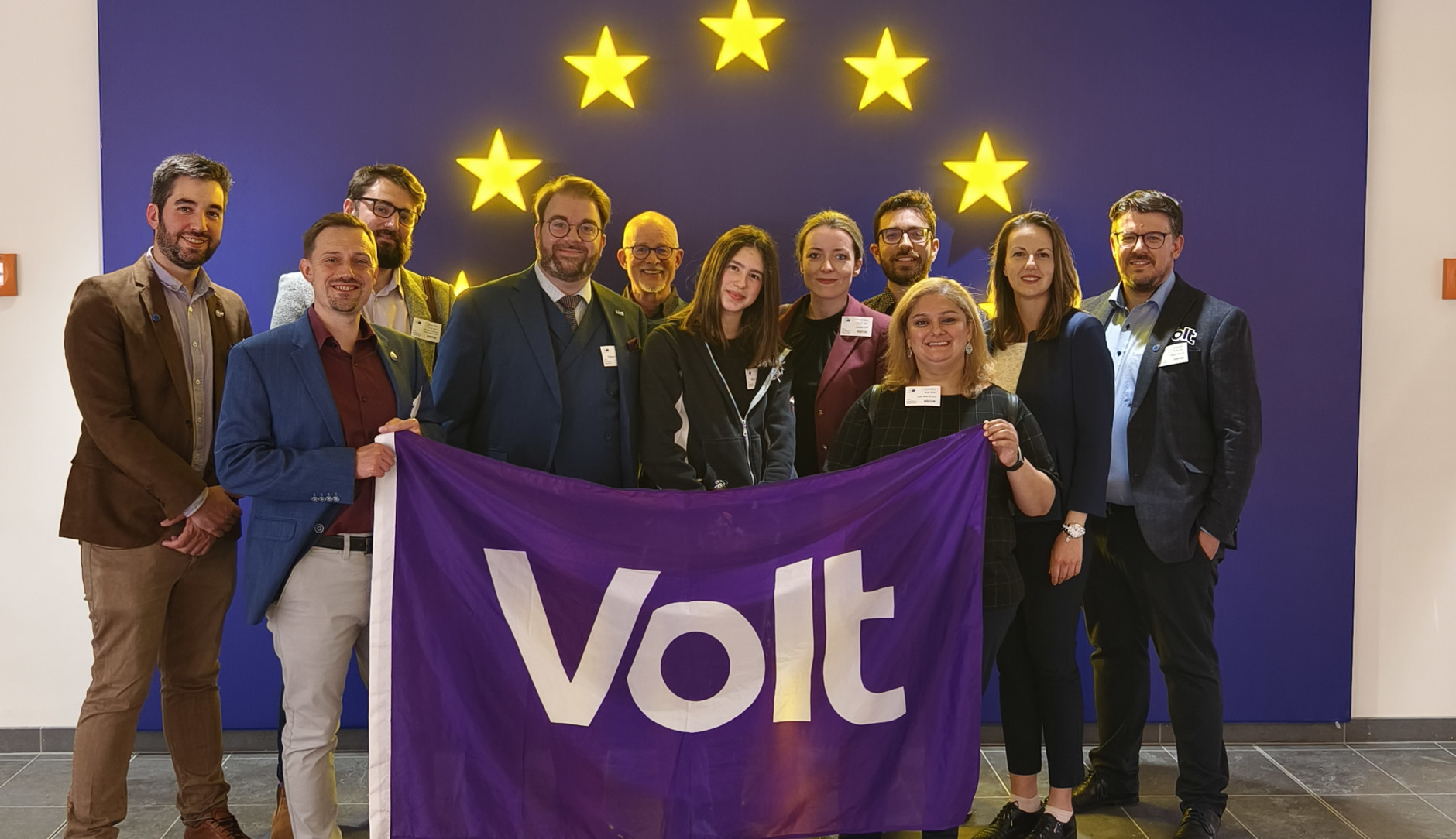 Candidates and members of Volt holding a Volt flag inside of the European Parliament in Luxembourg
