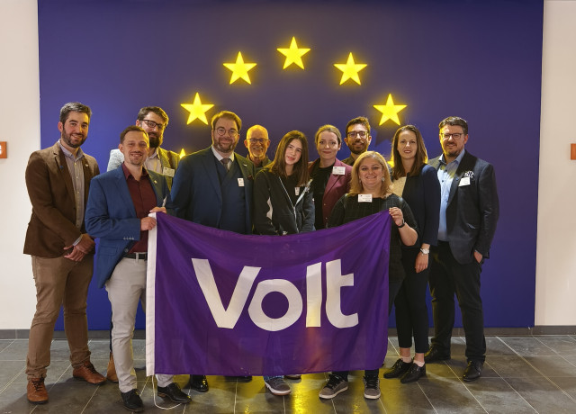 Candidates and members of Volt holding a Volt flag inside of the European Parliament in Luxembourg