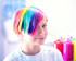 A child with hair dyed in rainbow colours and wearing a white T-shirt