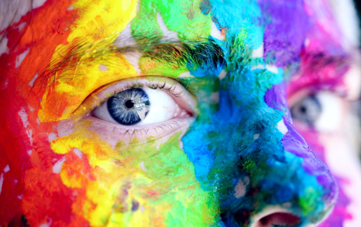 person, face painted in rainbow colours