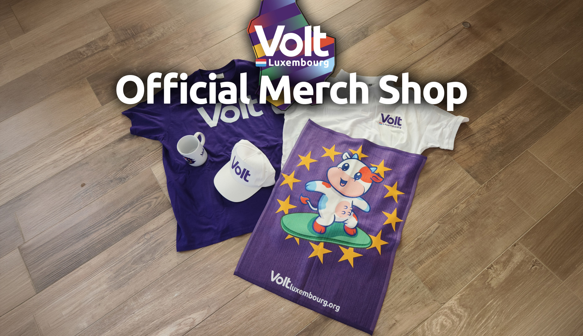 Volt merchandise lying on the floor, a t-shirt, a polo, a cup, a cap and a towel. Over it it says 